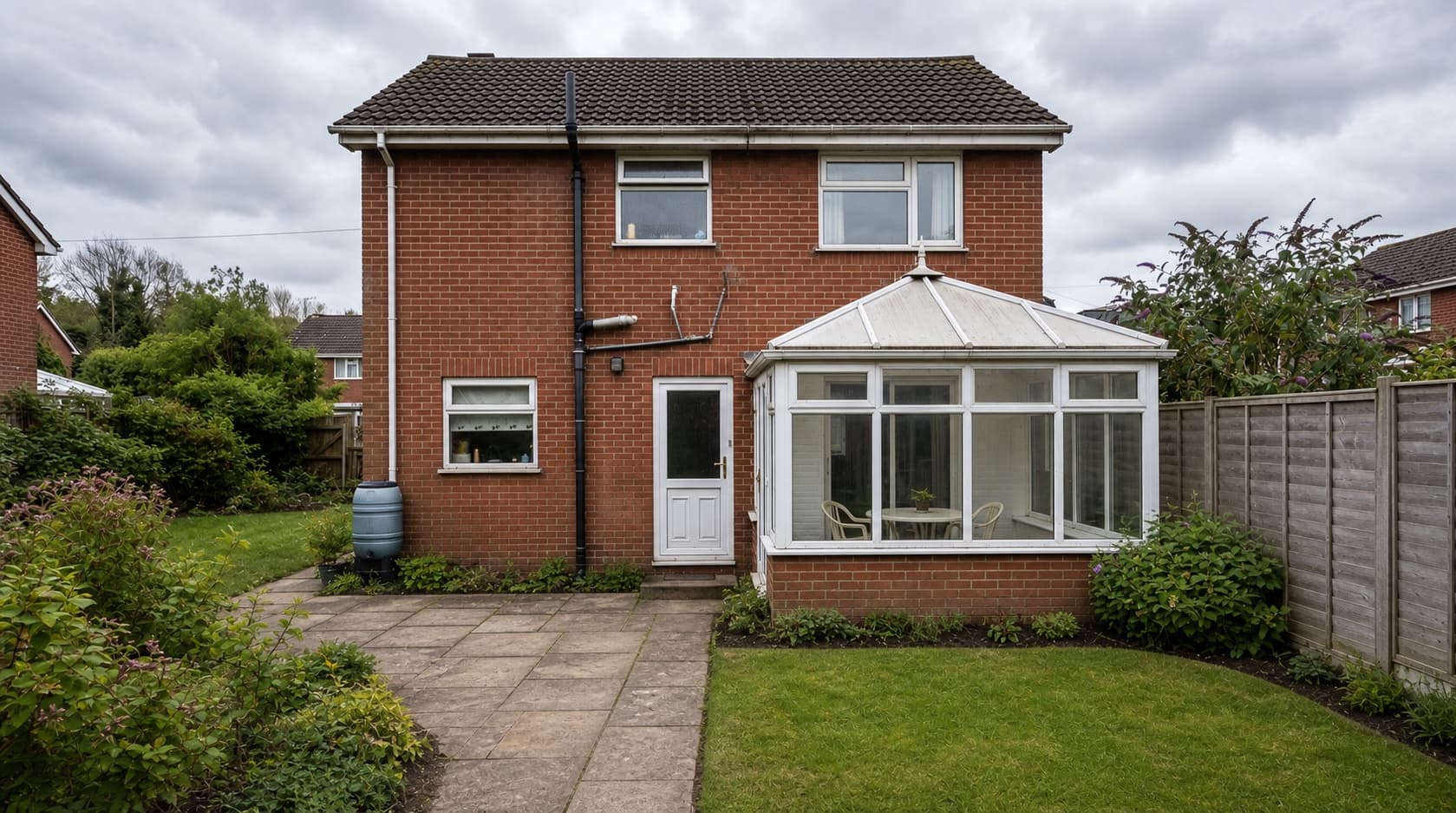 The maintained rear garden of a detached house with a dated conservatory, before work