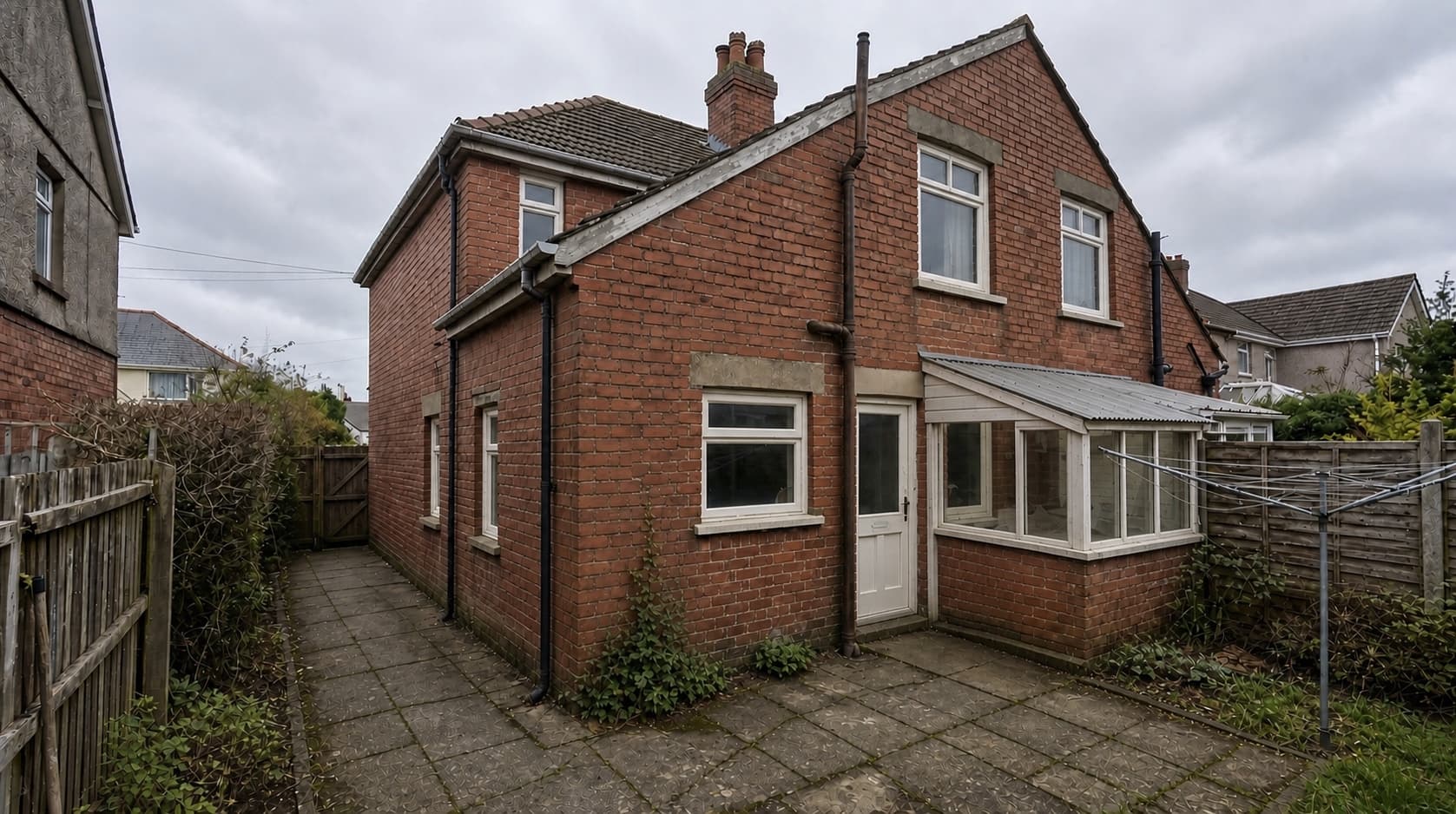 A dated side return with a weathered lean-to and worn paving, before work